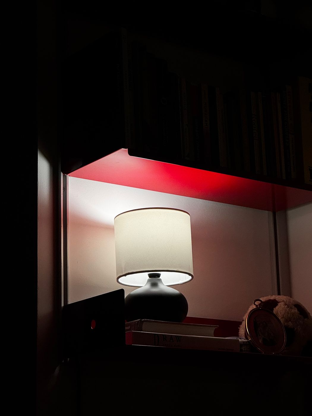 Red shelf lit by a table lamp at night